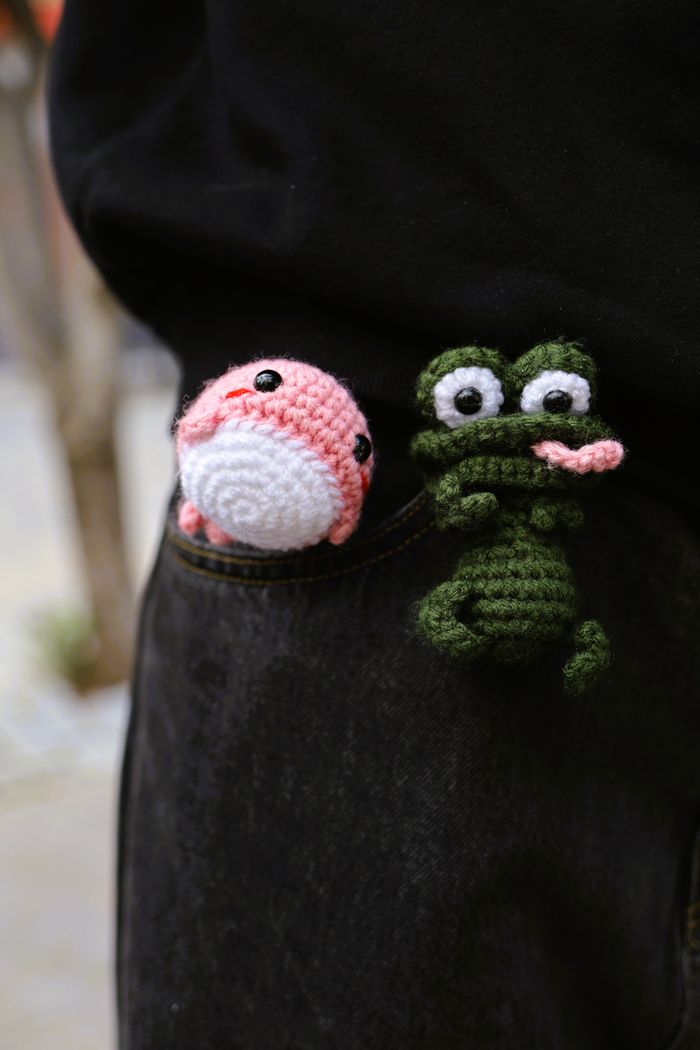 Two mini crochet creatures in a pocket
